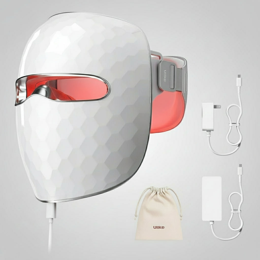 White LED face mask with red lights, power adapter, USB cable, and carrying bag on a gray background.